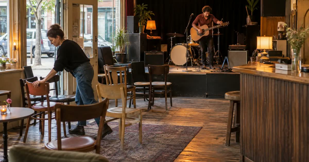 An owner arranges chairs while a musician sets up in a small independent music venue.