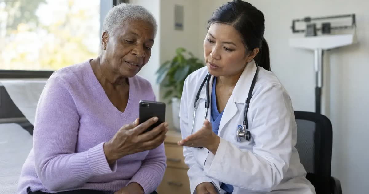 An older adult and a doctor discuss a smartphone during a clinic visit.